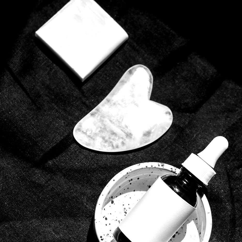 Gua sha stone and serum dropper still life in black and white